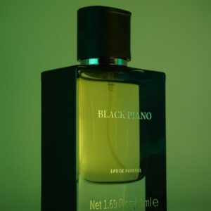 An artistic shot of a Black Piano perfume bottle with green lighting, showcasing its elegance and aroma.