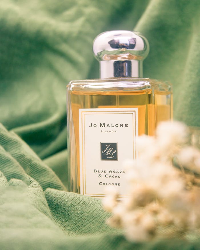 A luxurious Jo Malone perfume bottle styled on soft green fabric for an elegant still life shot.